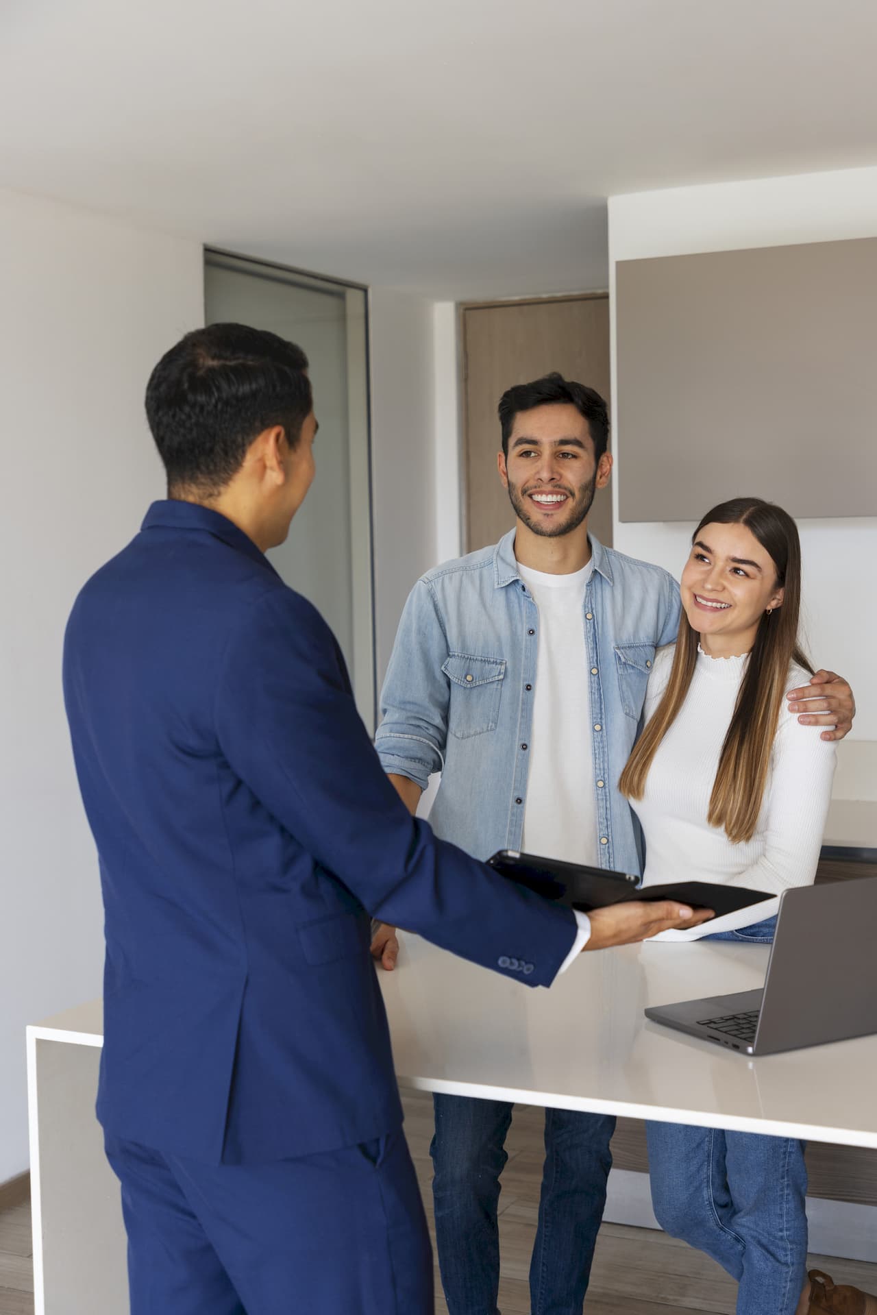 Young couple meeting with a male agent in an office setting, smiling and engaging in conversation